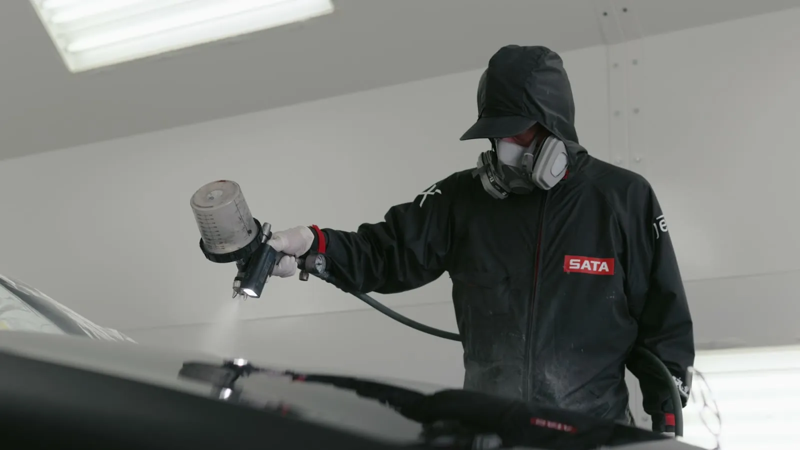 Technician spraying Peel Clear on a hood